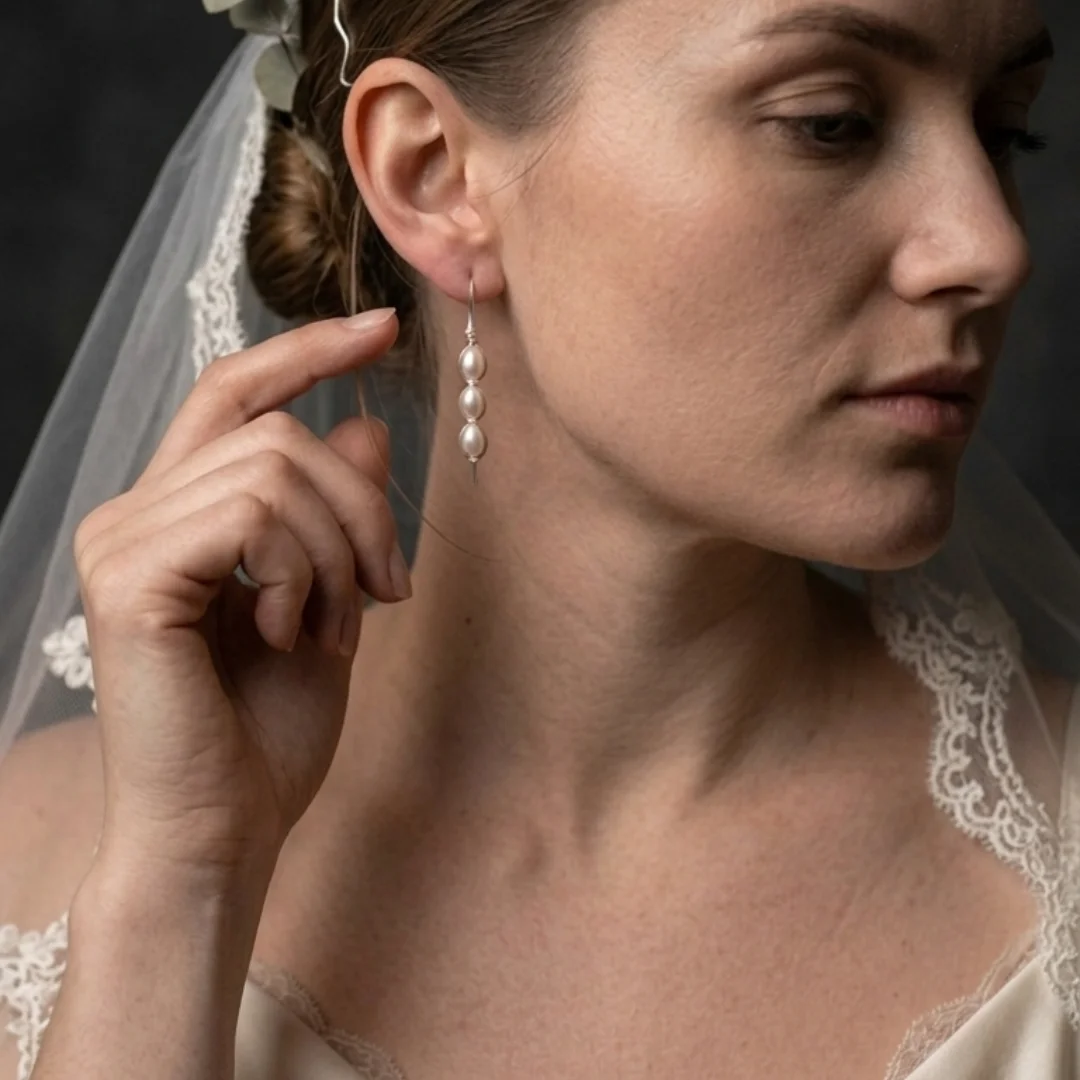 Wire wrapped pearl earrings worn — long marquise drop earring with pearl cage, REPIOR® handmade jewellery England
