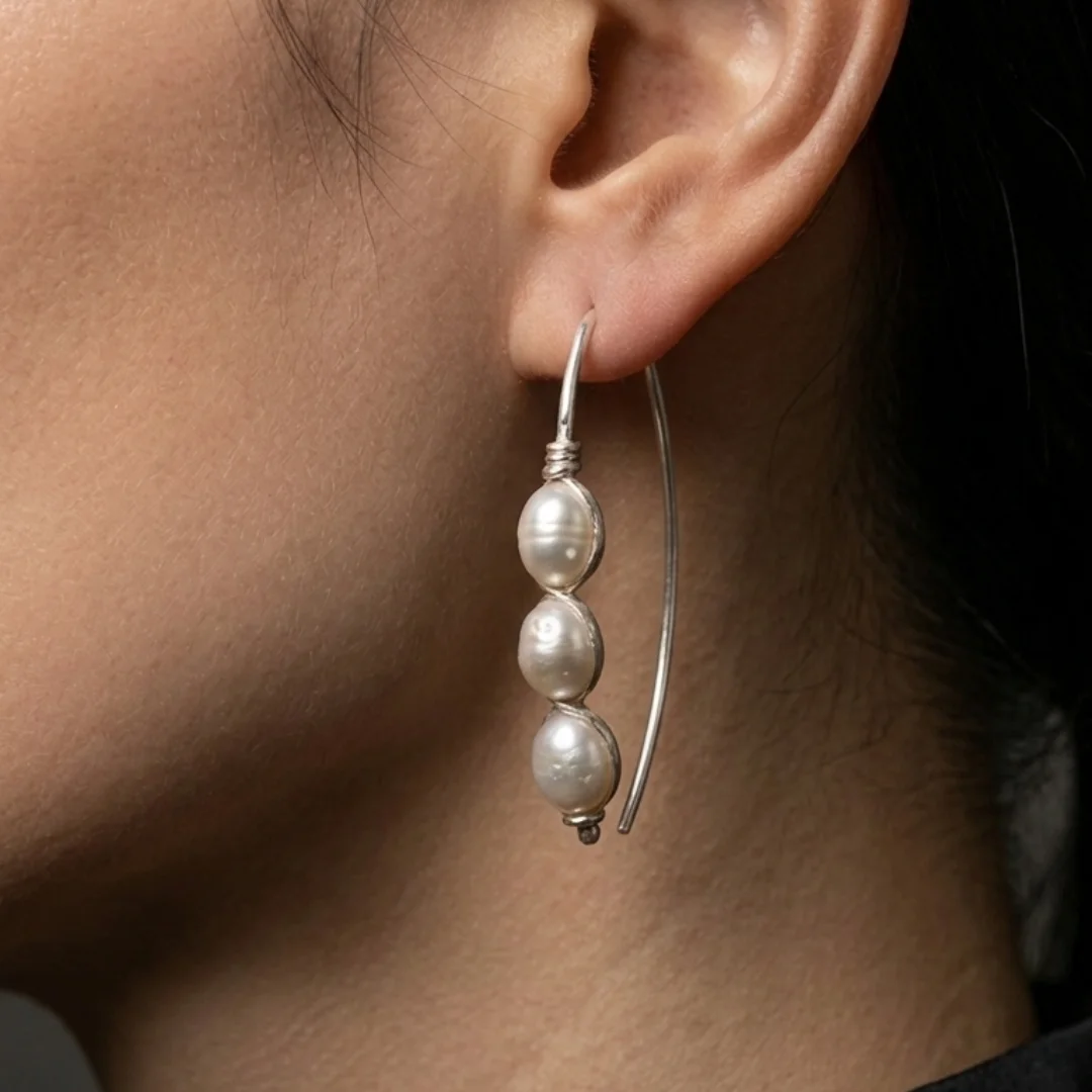 Wire wrapped pearl earrings worn — long marquise drop earring with pearl cage, REPIOR® handmade jewellery England